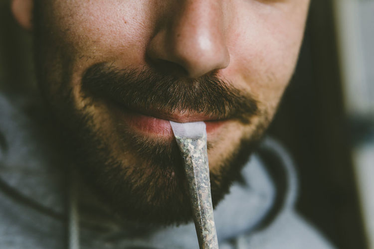 Midsection of bearded man carrying marijuana joint in mouth
