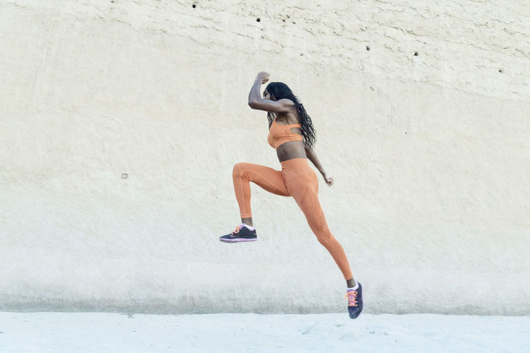 Side view of woman running on wall