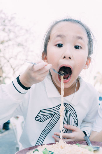 Portrait of cute girl eating noodles