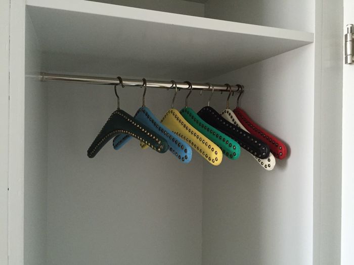 Colorful coathangers hanging on rod in wardrobe