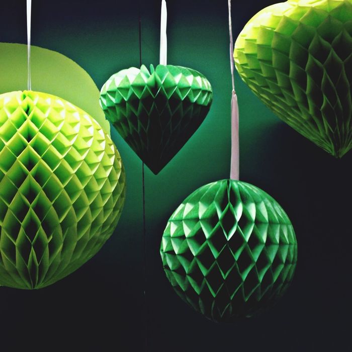 Close-up of green hanging lights against green background