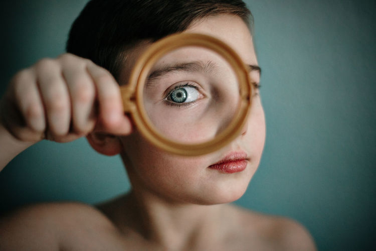 Close-up portrait of boy looking through magnifying glass