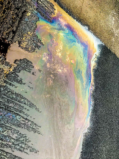Reflection of rainbow in puddle on road