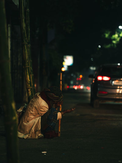 Beggar on street in city at night