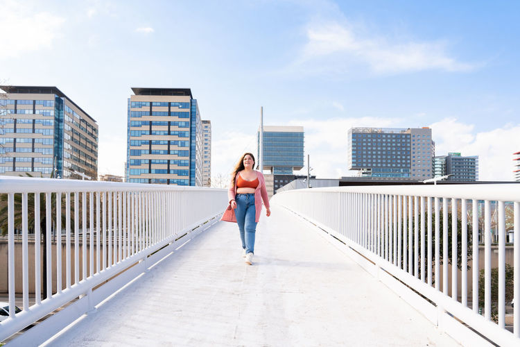 Full length of woman walking on footbridge against sky
