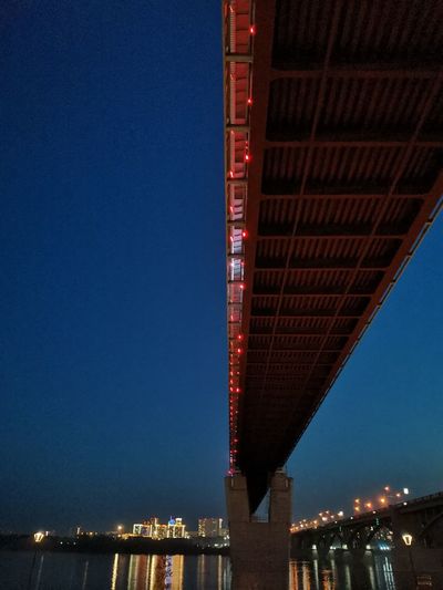 Low angle view of illuminated bridge against clear blue sky