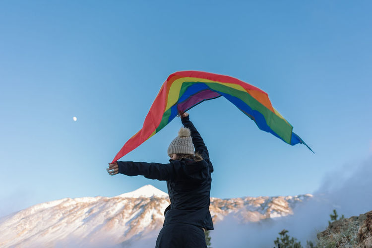 Person on mountain peak waving lgbt flag
