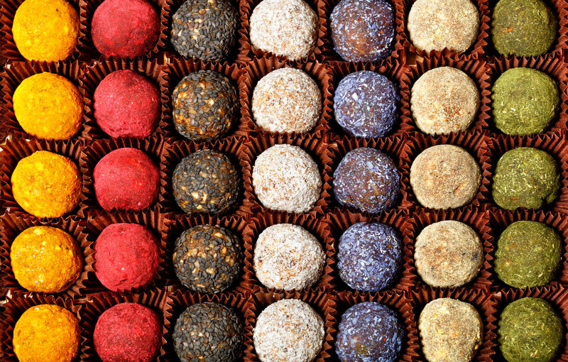 Collection of handmade energy balls with various fillings in brown paper baskets, top view. 