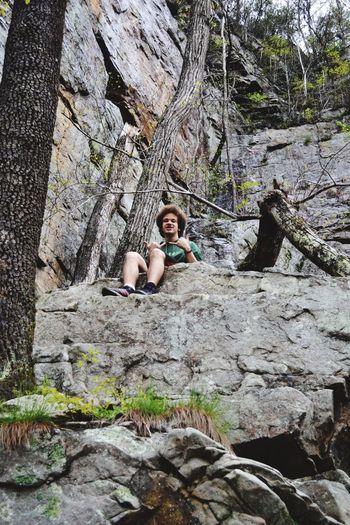 Portrait of smiling teenage boy sitting on rock