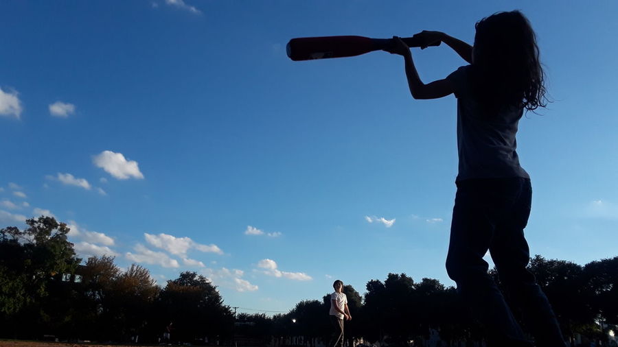 Low angle view of silhouette people playing against sky