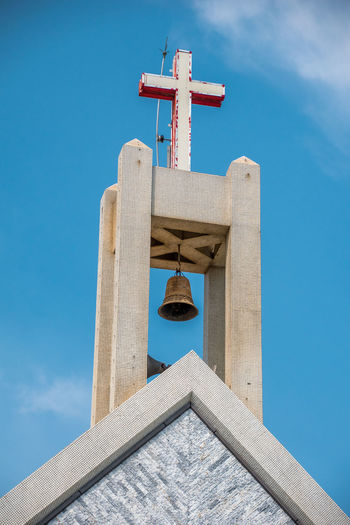 Low angle view of cross on building against blue sky