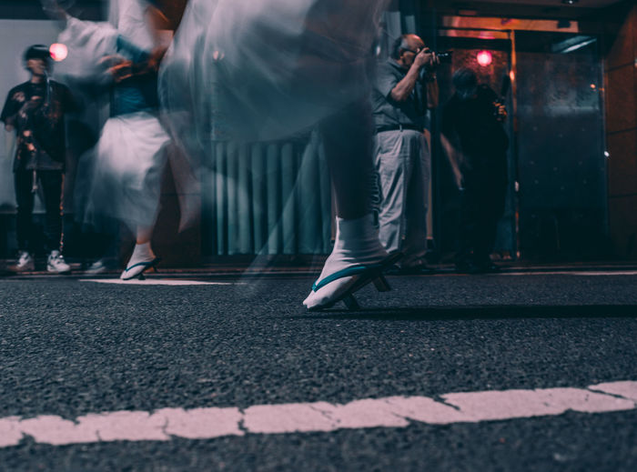 Blurred motion of people jumping over road