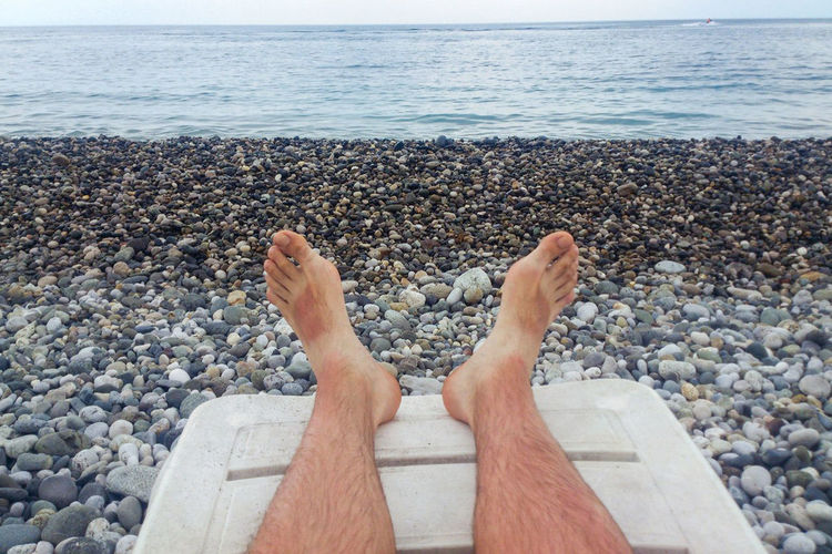 Men's hairy legs on the beach by the sea