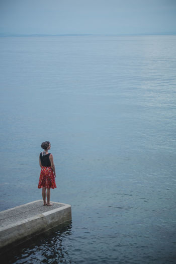 Woman standing on jetty by sea