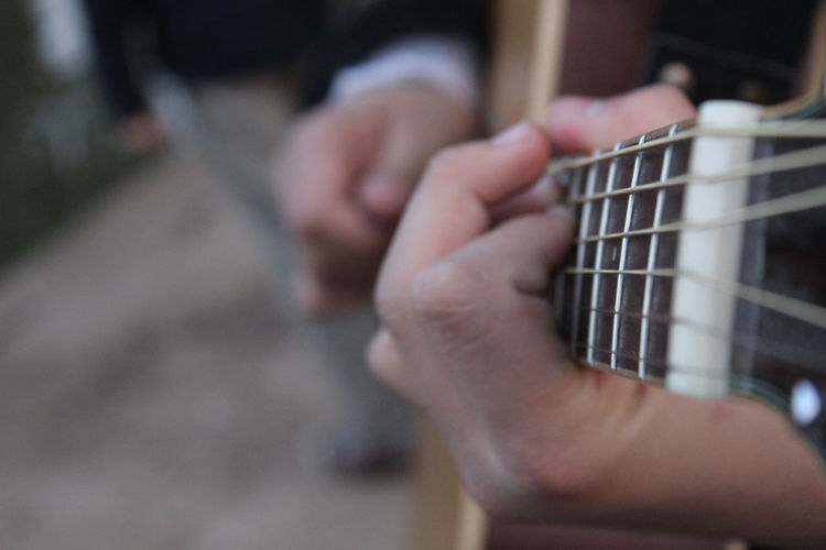 Close-up midsection of man playing guitar on street