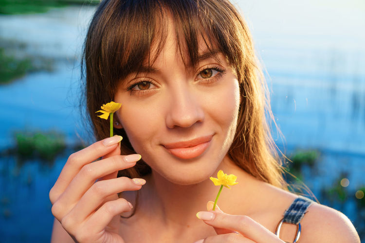 Portrait of a young woman holding flowers near her face