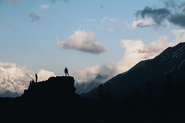 Silhouette people standing on mountain against sky