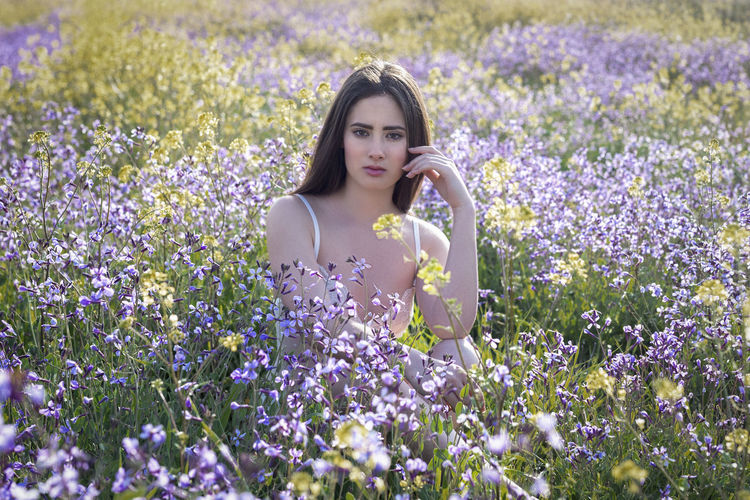 Portrait of woman with purple flowers in field