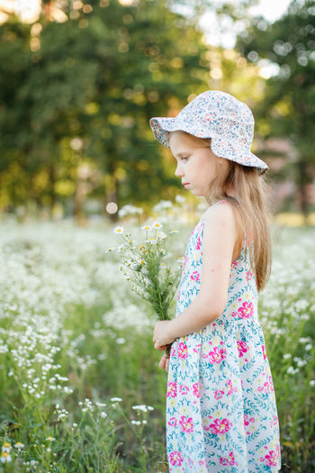 Side view of girl standing against plants