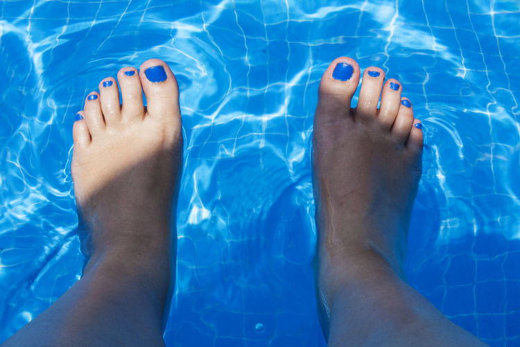 Low section of bare feet in swimming pool