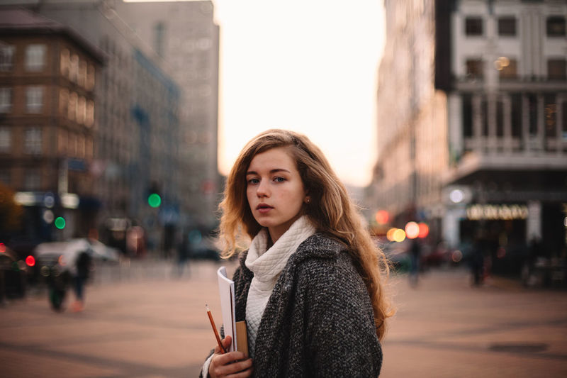 Portrait of young woman standing on city street