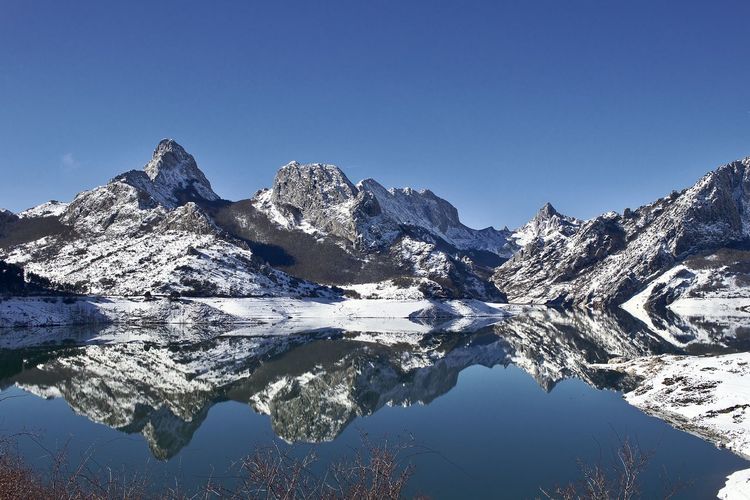 Scenic view of snowcapped mountains against clear blue sky reflected in the lake