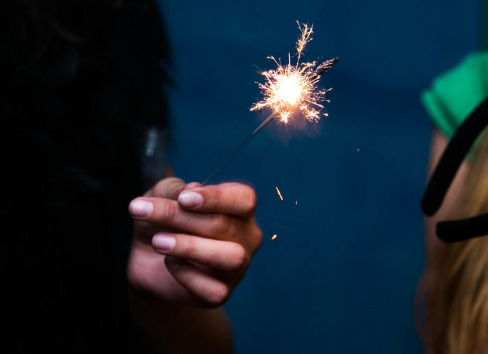 Cropped hand holding illuminated sparkler