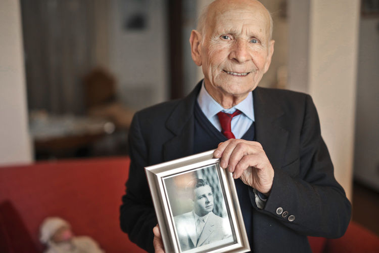 Portrait of an elderly man with a souvenir photo as a young man