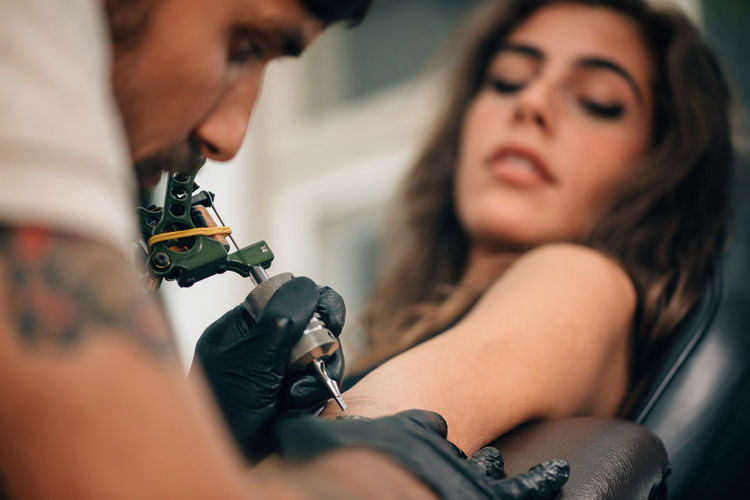 Close-up of mam making tattoo on woman hand