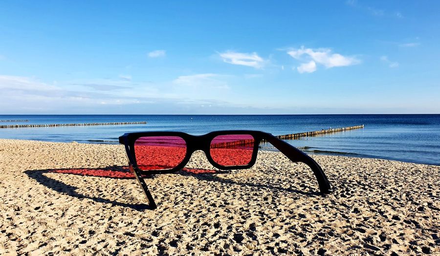 Sunglasses on beach against sky