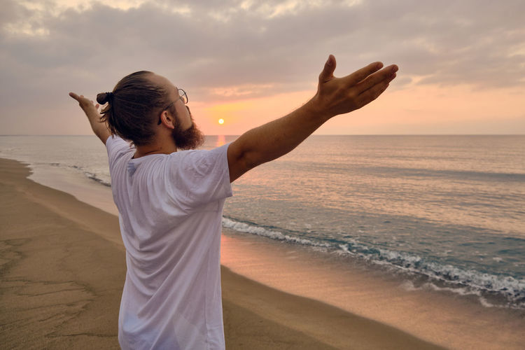 Man doing surya namaskar or salute to the sun or sun salutation. man practices yoga at sea beach