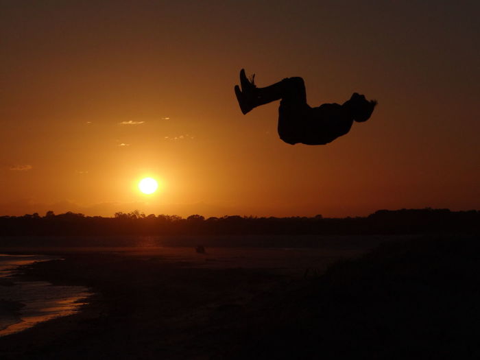 Silhouette of person jumping at sunset