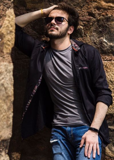 Man with hand in hair standing by wall