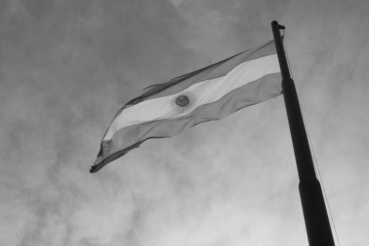 Low angle view of argentinian flag against cloudy sky