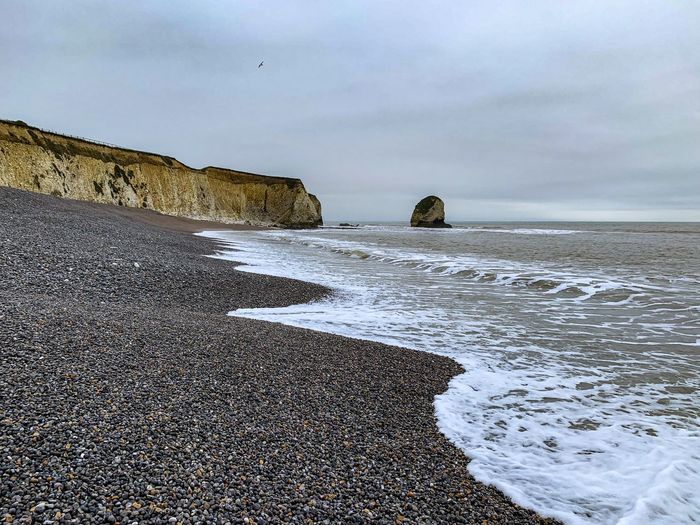 Rock formations on beach against sky