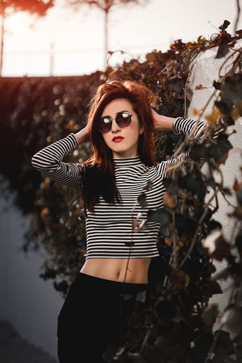 Portrait of woman in sunglasses standing against wall