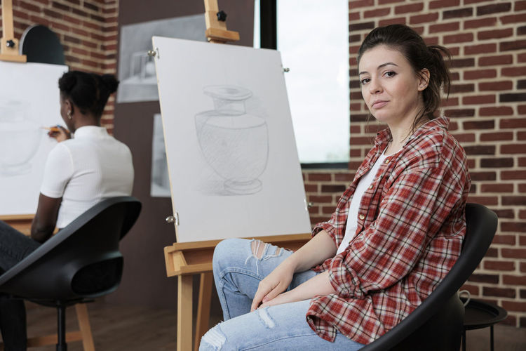 Side view of woman sitting in drawing class