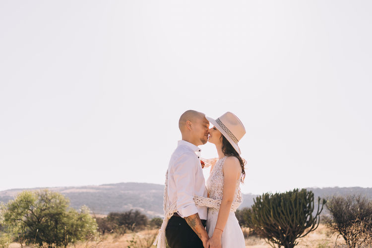 Side view of couple standing against clear sky