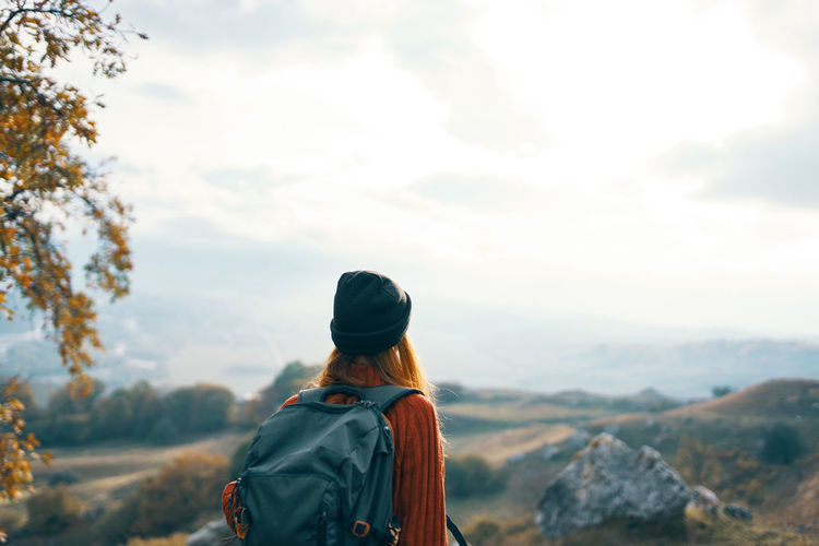 Rear view of woman looking at mountains against sky