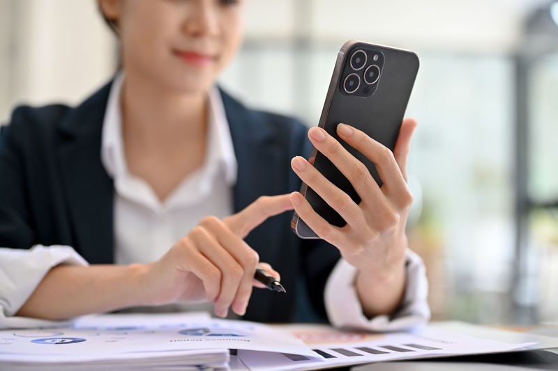 Midsection of woman using mobile phone at office
