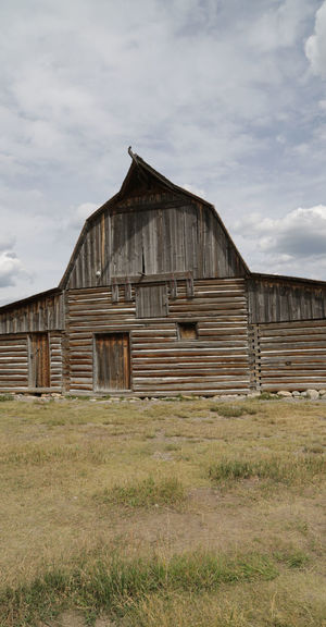 Old barn on field against sky