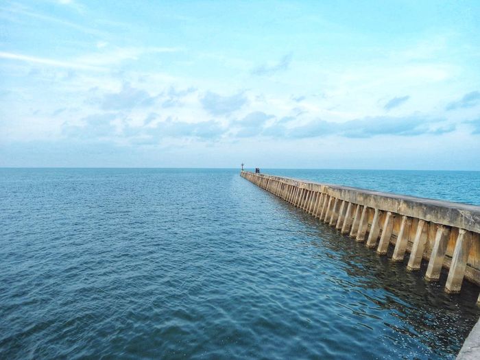 Wooden posts in sea against sky