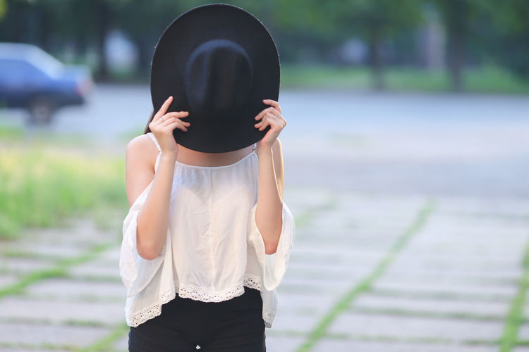 Midsection of woman wearing hat standing outdoors