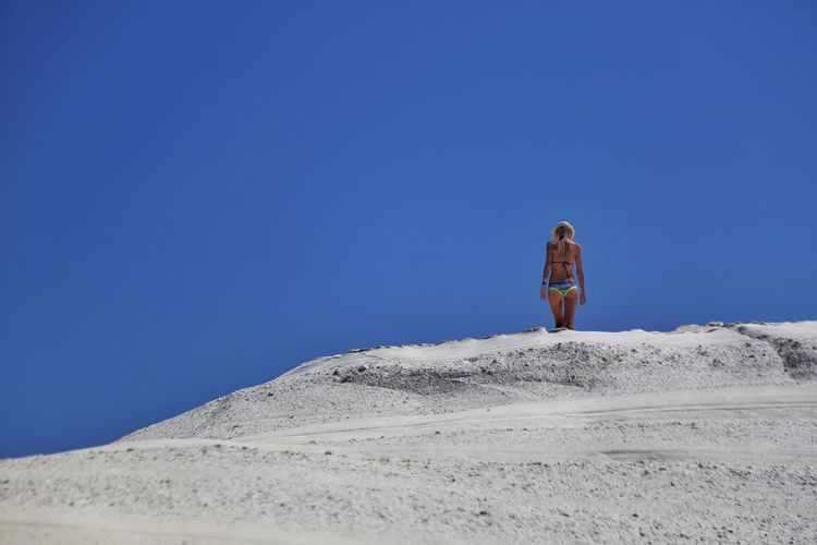 Woman standing on land against clear blue sky