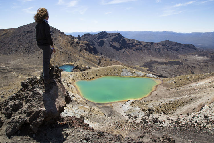 One male hiker, on top of rock, looking at emerald lakes, tongariro
