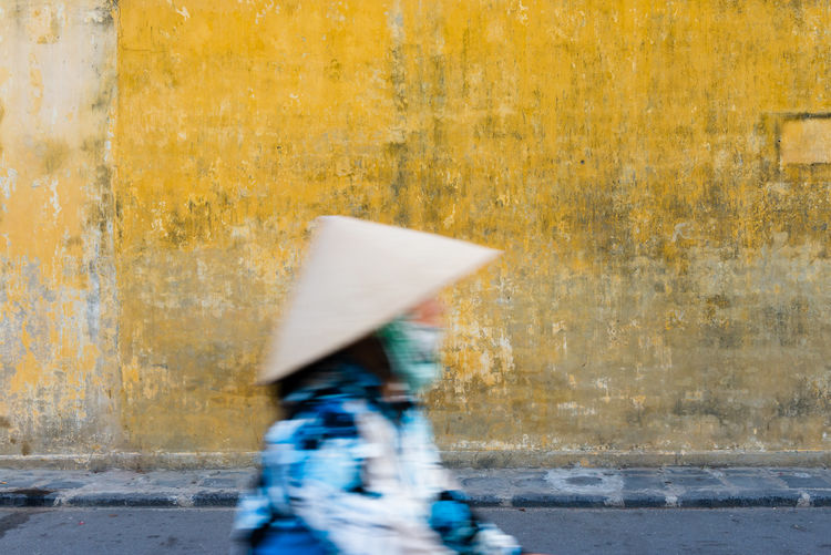Blurred motion of person wearing hat walking on street