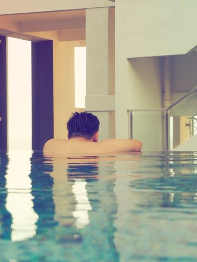 Rear view of man relaxing in swimming pool