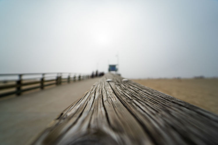Surface level of wooden pier on beach against clear sky