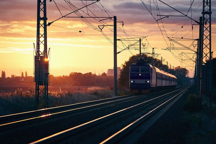 Passenger train of public transport on railroad track at beautiful sunrise.
