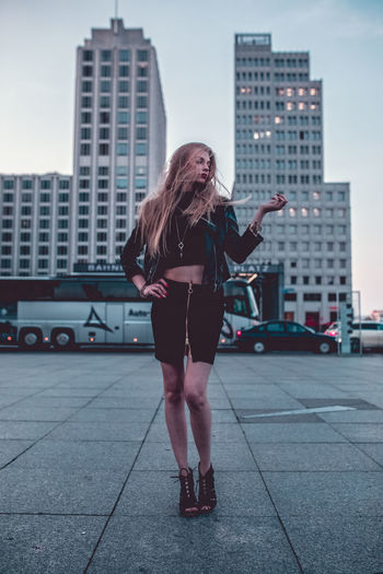 Full length of woman standing in city at dusk